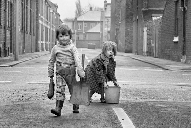 Children scoop up horse manure from the street