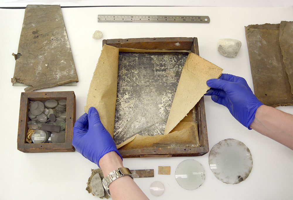 Two gloved hands show materials from James Watt's workshop.