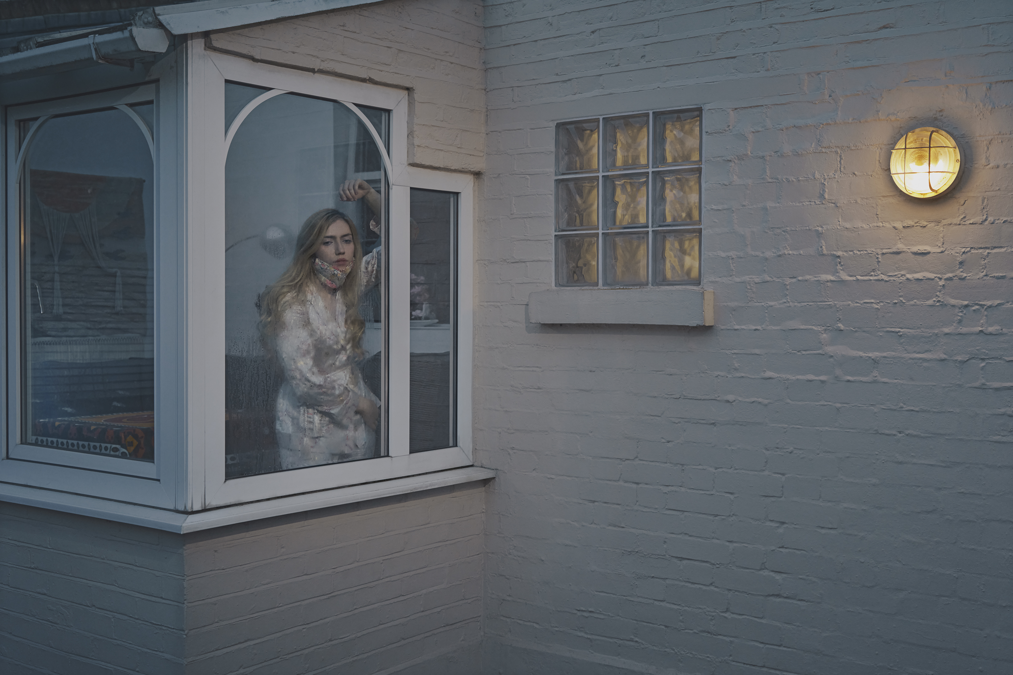 Chloe looks out of her window in dressing gown