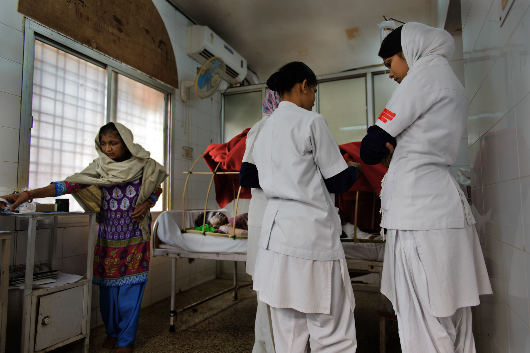 Nurses stand by a patient on hospital bed