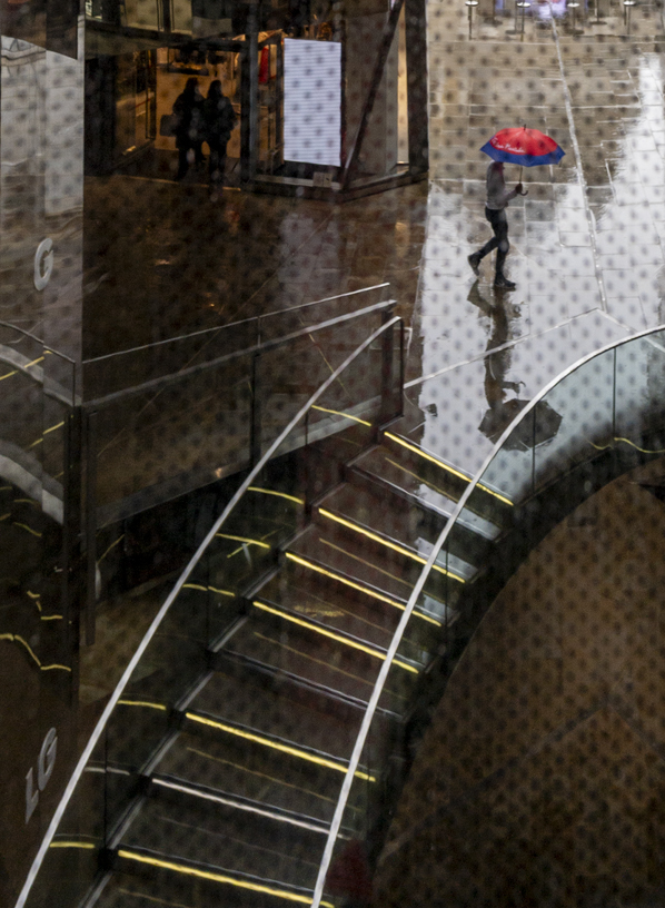 Rainy street scene featuring a stairway and figure with a red umbrella